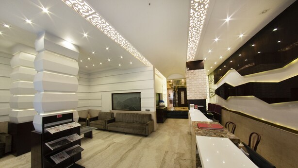 A modern hotel lobby with a reception desk, seating area, and decorative lighting. - Hotel Manama (Mumbai)