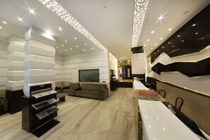 A modern hotel lobby with a reception desk, seating area, and decorative lighting. - Hotel Manama (Mumbai)