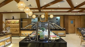 A buffet setup with multiple food stations, a wooden ceiling with exposed beams, and hanging pendant lights.