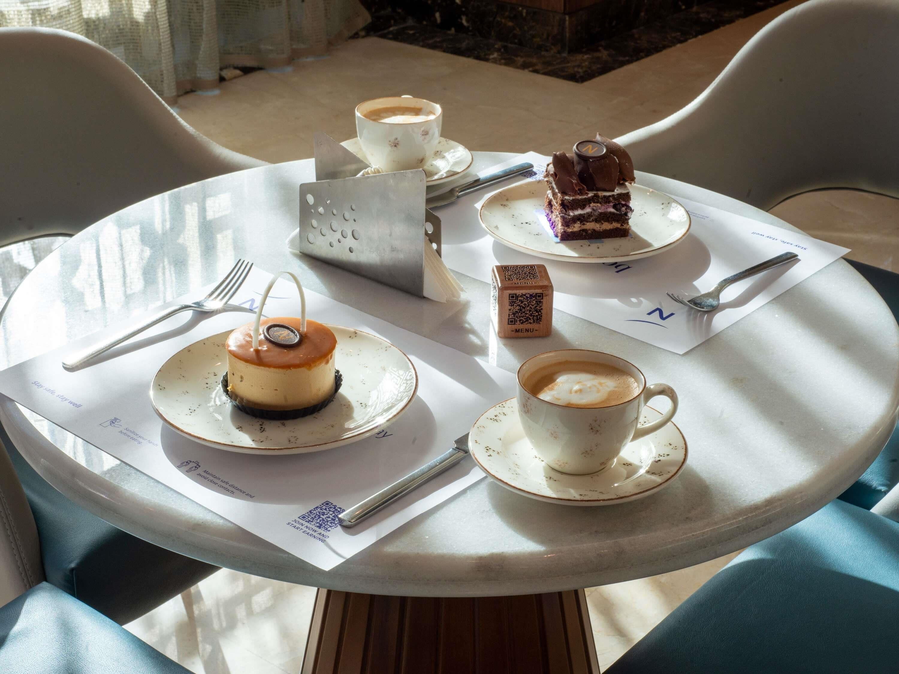 Una mesa redonda con un postre, una taza de café y un menú.