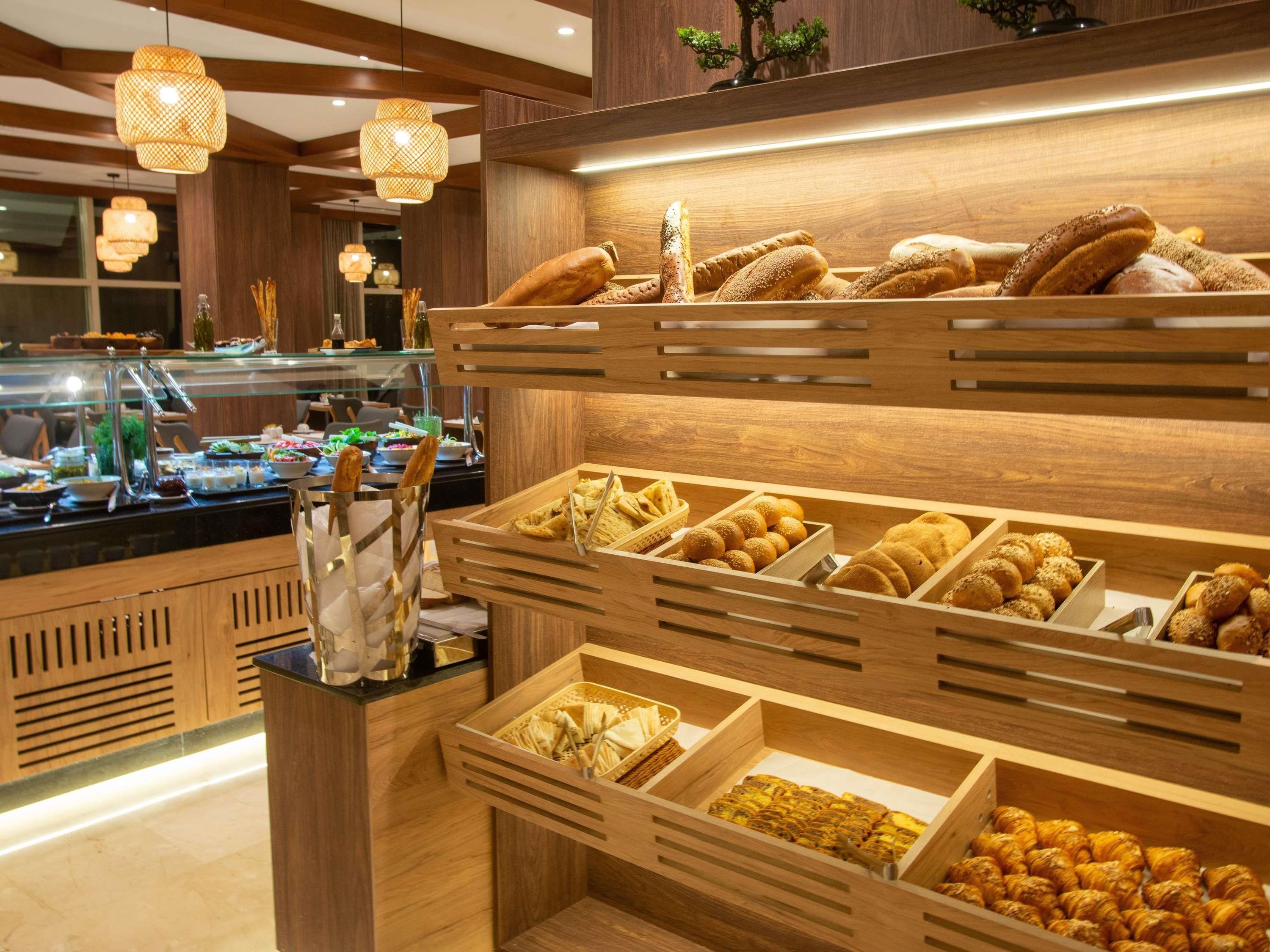 Un bufé con diversas opciones de panadería y un expositor de vidrio con utensilios.