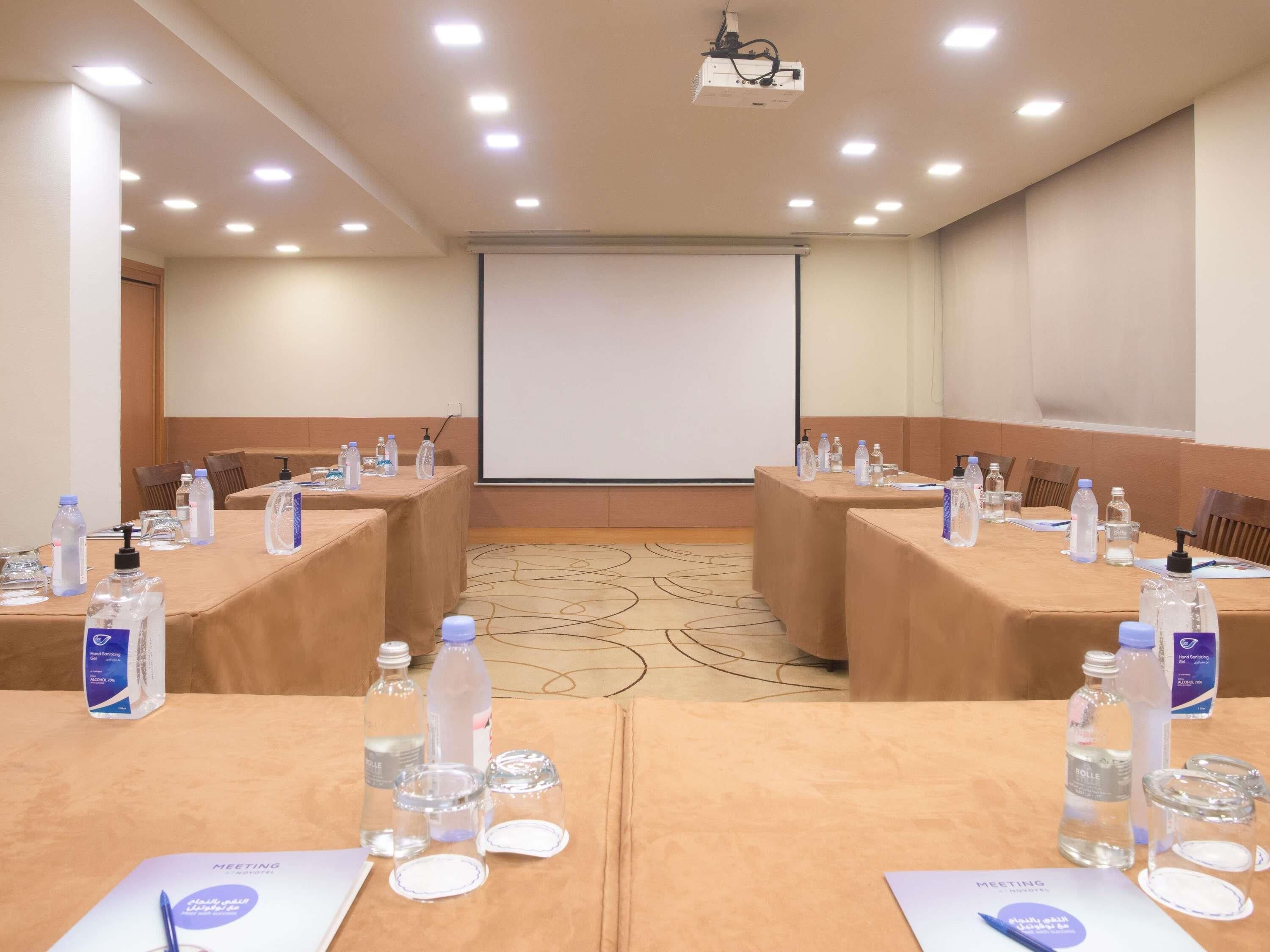 A conference room with tables set up for a meeting, equipped with water bottles and nameplates.