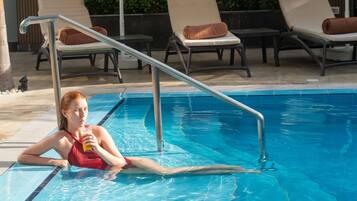 A pool area with lounge chairs and a metal pool ladder.