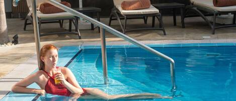 A pool area with lounge chairs and a metal pool ladder.