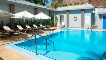 Una piscina al aire libre, sillones reclinables de piscina