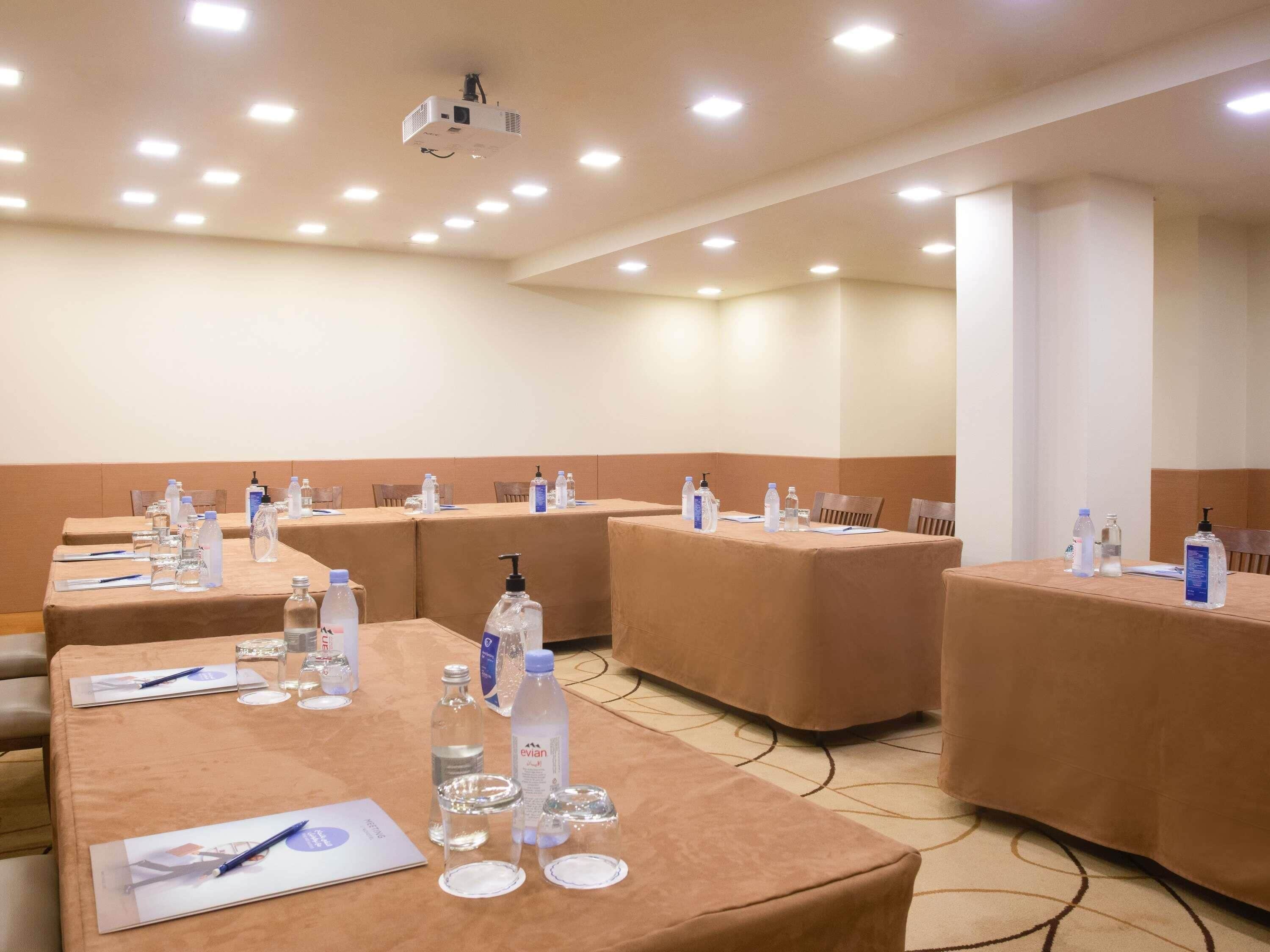 A conference room with tables set for meetings, equipped with water bottles, glasses, and notepads.