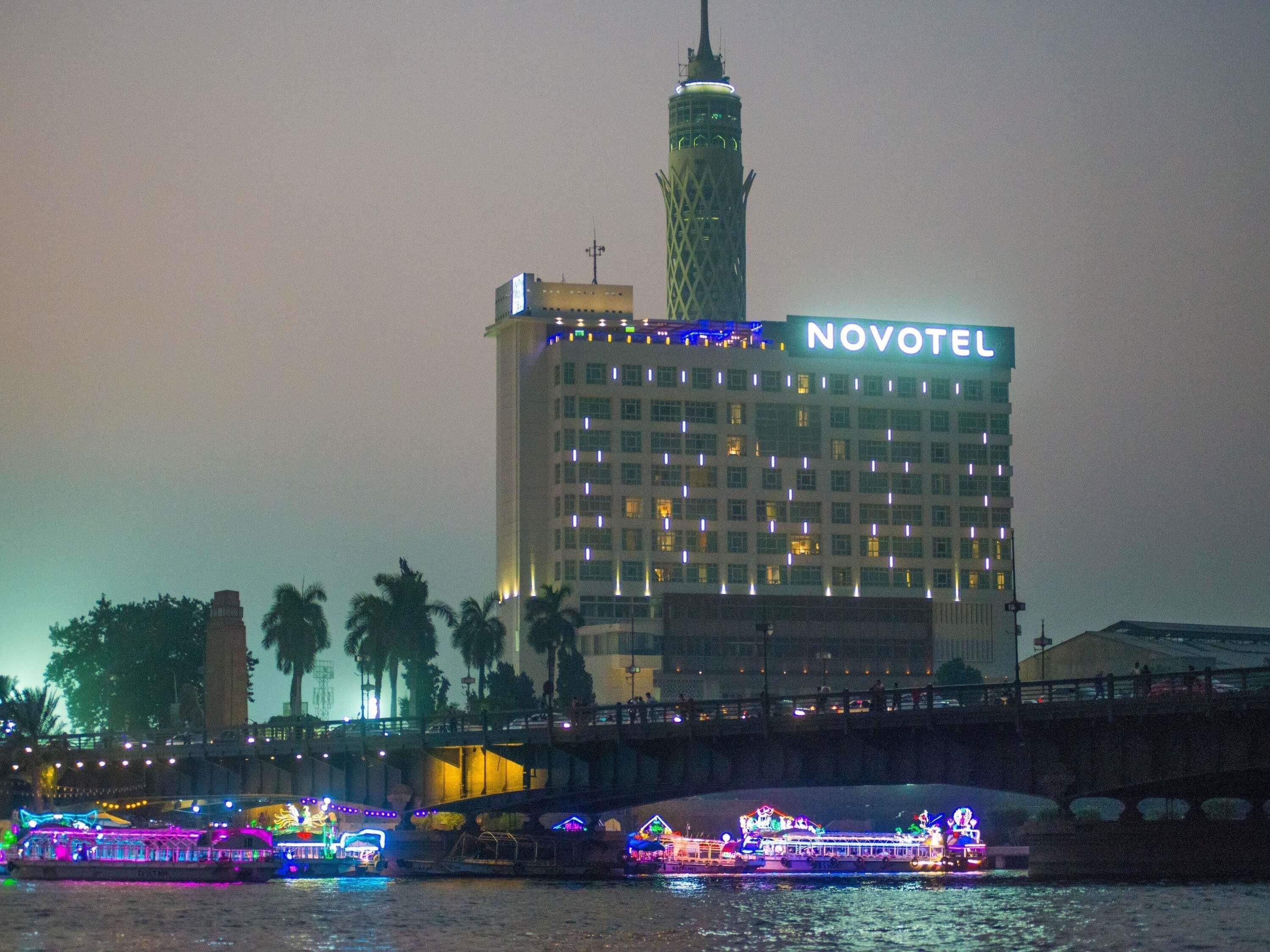 Un hôtel doté d’une tour imposante et dont la façade est illuminée par le nom « NOVOTEL ».