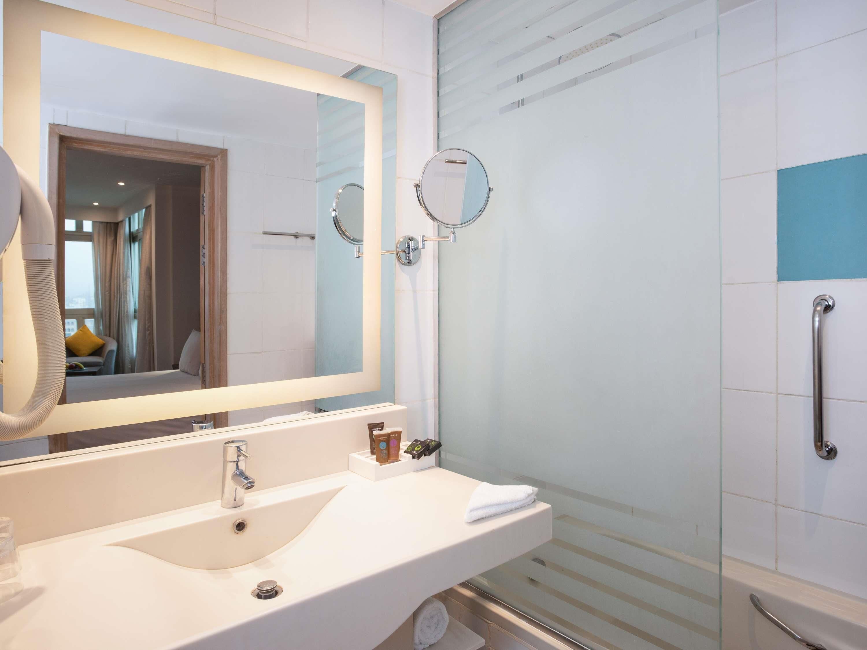 A modern bathroom with a large mirror, a sink, a shower, and a glass-enclosed shower area.