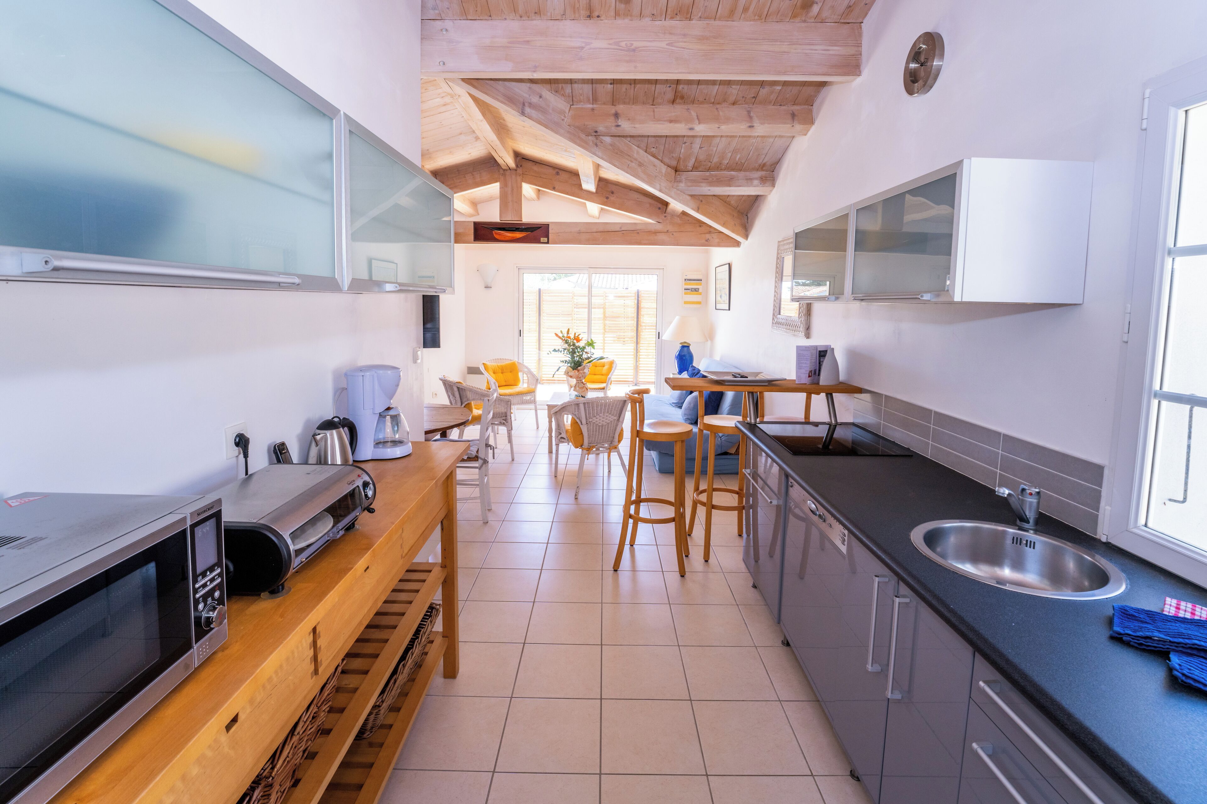 A modern kitchen with a wooden countertop, built-in appliances, and a dining area with chairs and a table.