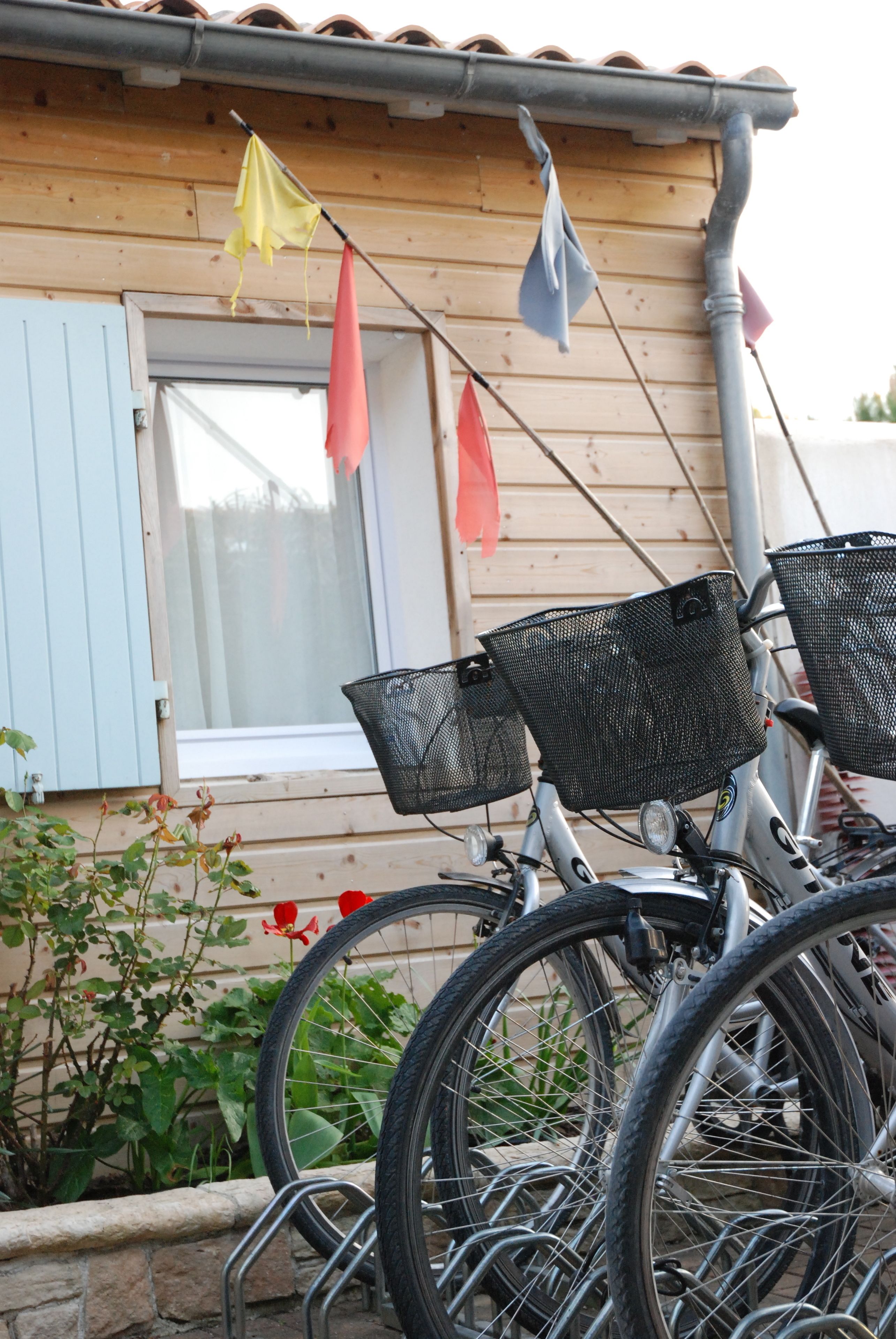 A bicycle parked in front of a wooden house with a window and a door.