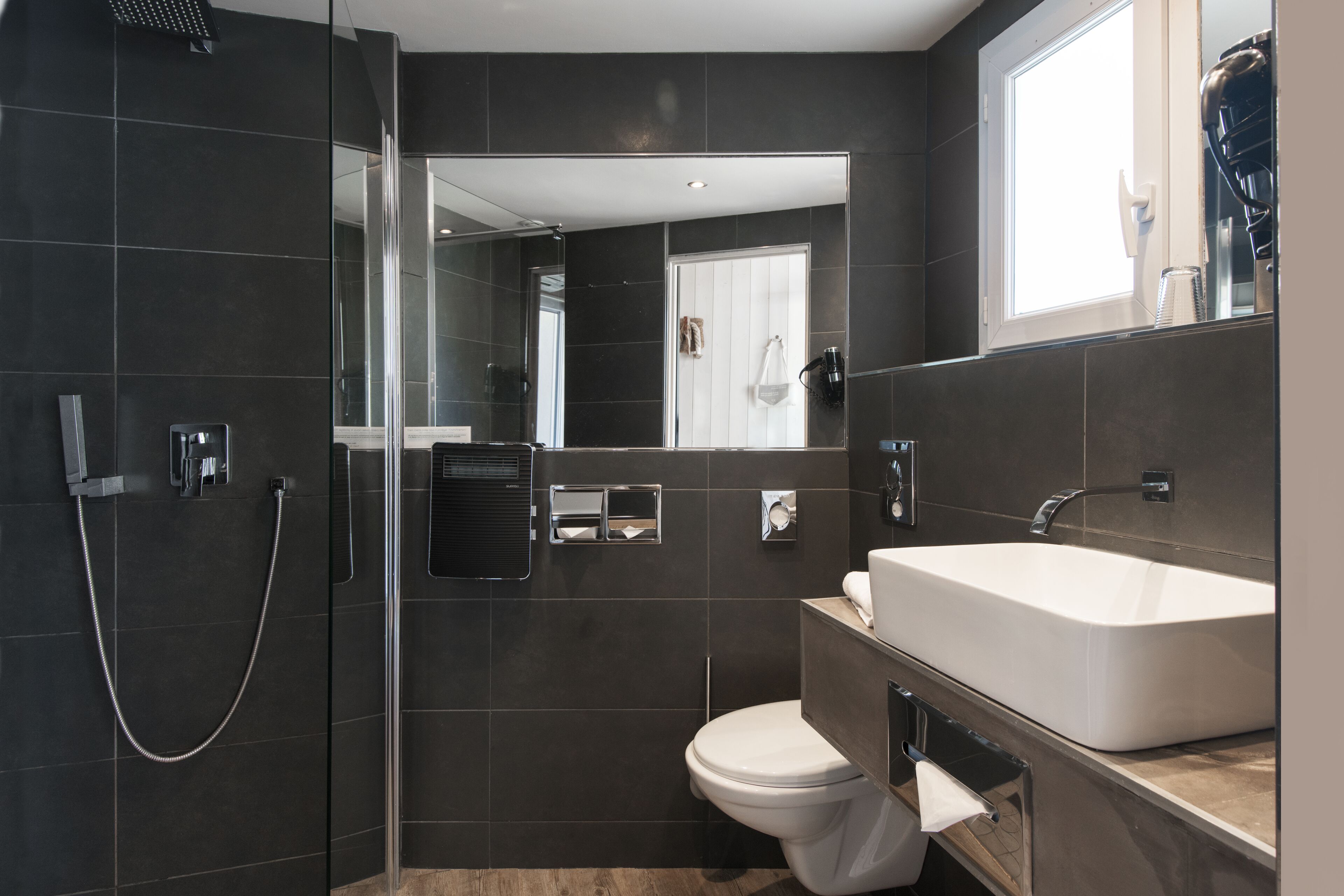 A modern bathroom with a walk-in shower, a toilet, and a large sink.