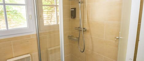 A shower with a glass door, a window, and a radiator.