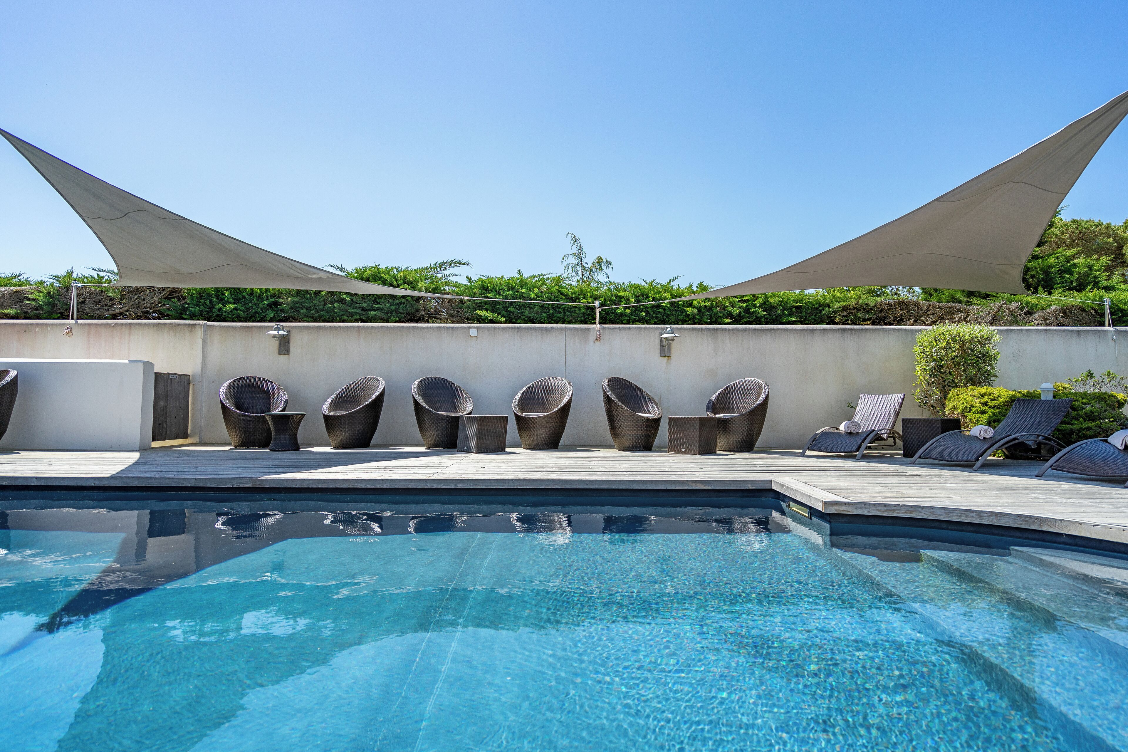 Une piscine avec des chaises longues et un espace ombragé.