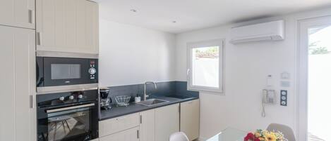 A modern kitchen with built-in appliances, a glass dining table, and a window with a view.