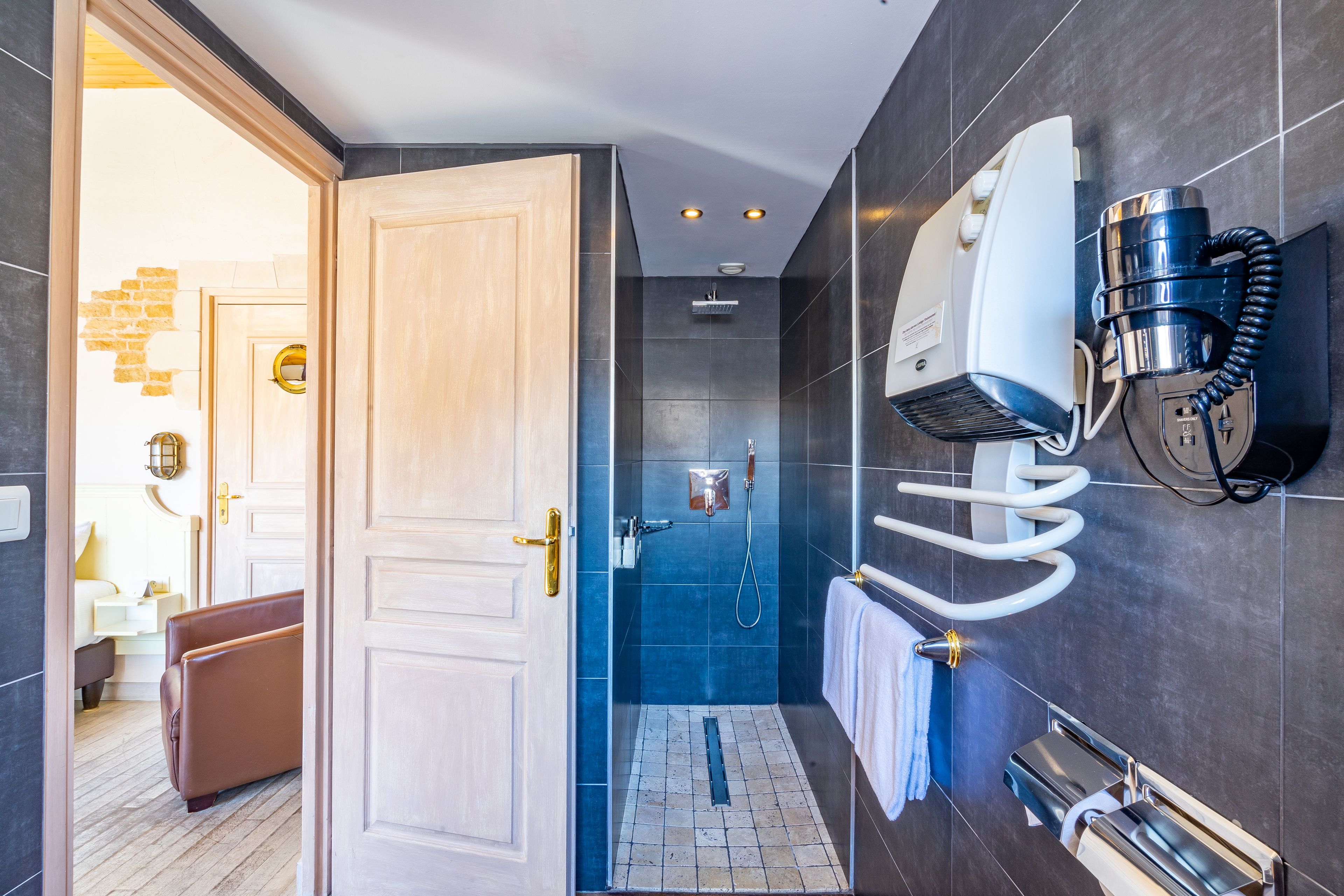 A modern bathroom with a shower, a towel rack, and a built-in heater.