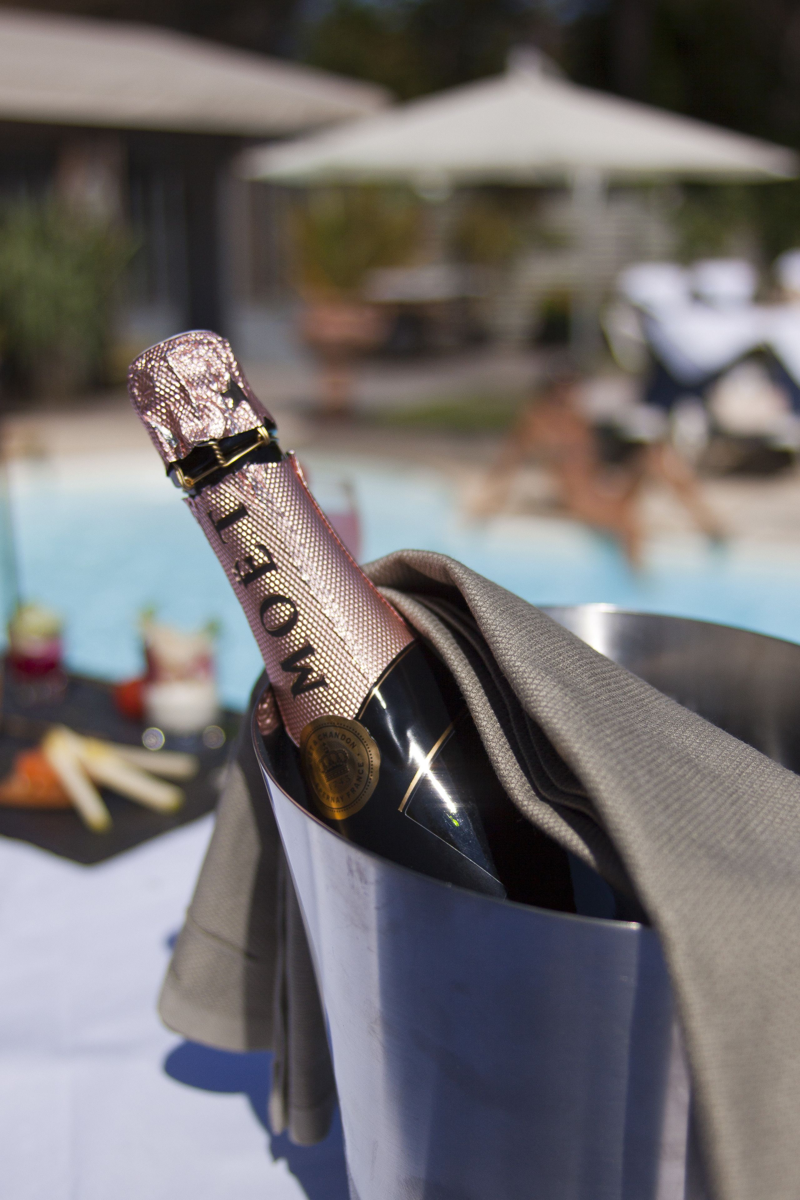 A bottle of champagne in a metal container with a cloth napkin.