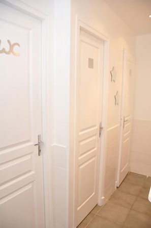 A hallway with white doors, each with a small square window.