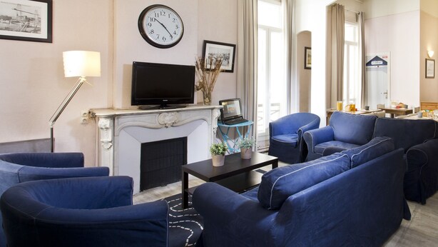 A modern living room with a fireplace, a television, and blue sofas. - Hotel Sylvabelle (Marseille)