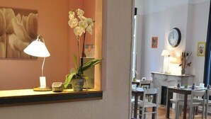 A living room with a sofa, a colorful striped rug, a lamp, and a potted plant. - Hotel Sylvabelle (Marseille)