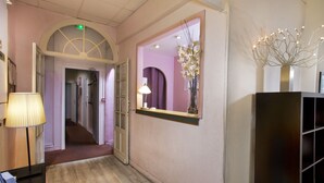 A hallway with a lamp, a mirror, and a vase with flowers. - Hotel Sylvabelle (Marseille)