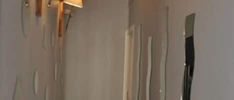 Un pasillo estrecho con suelo de baldosas y paredes decoradas con espejos reflectantes y deformantes.