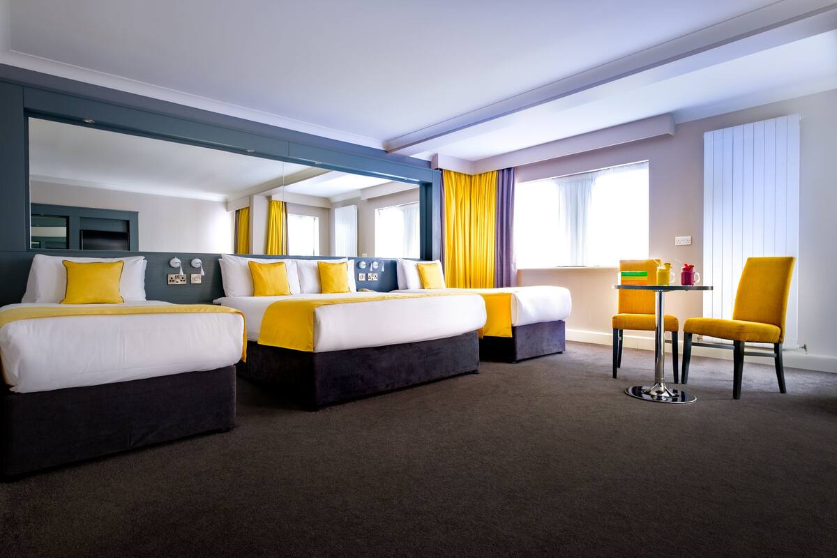 Une chambre d’hôtel avec deux lits, une petite table et une chaise.