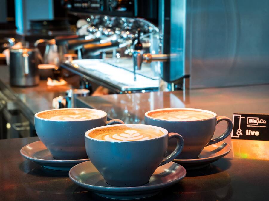 Three cups of coffee with latte art on a bar counter in a cafe.