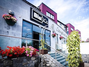 Welcome to Bia & Co., a contemporary building with a distinctive entrance featuring a metal staircase and curved archway.