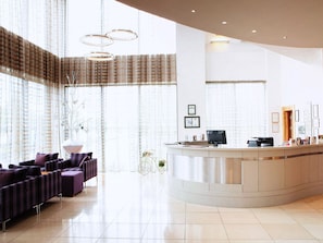 Relax in our spacious lobby, featuring a reception desk, comfortable seating area, and large windows with views of the outside.