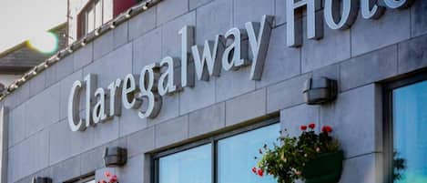 The exterior of Claregalway Hotel with a stone facade, large windows, and flower boxes on the windowsills.