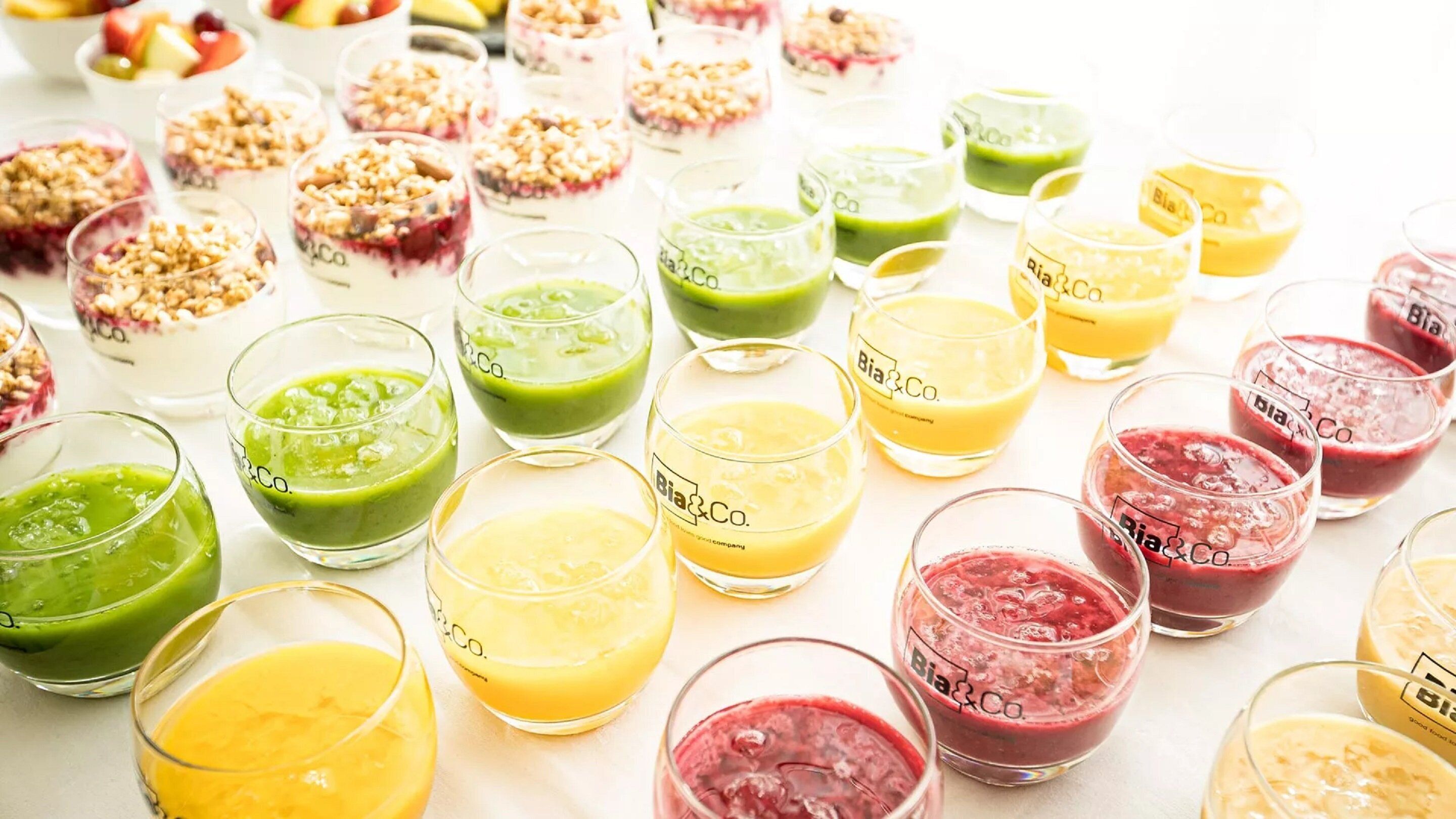 A variety of colorful beverages in glasses, some with a label that reads "Bia&Co."