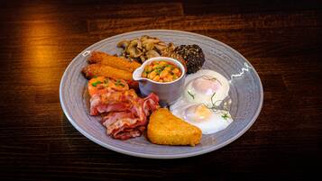 Un plato de comida para el desayuno con tocino, huevos, champiñones y frijoles.