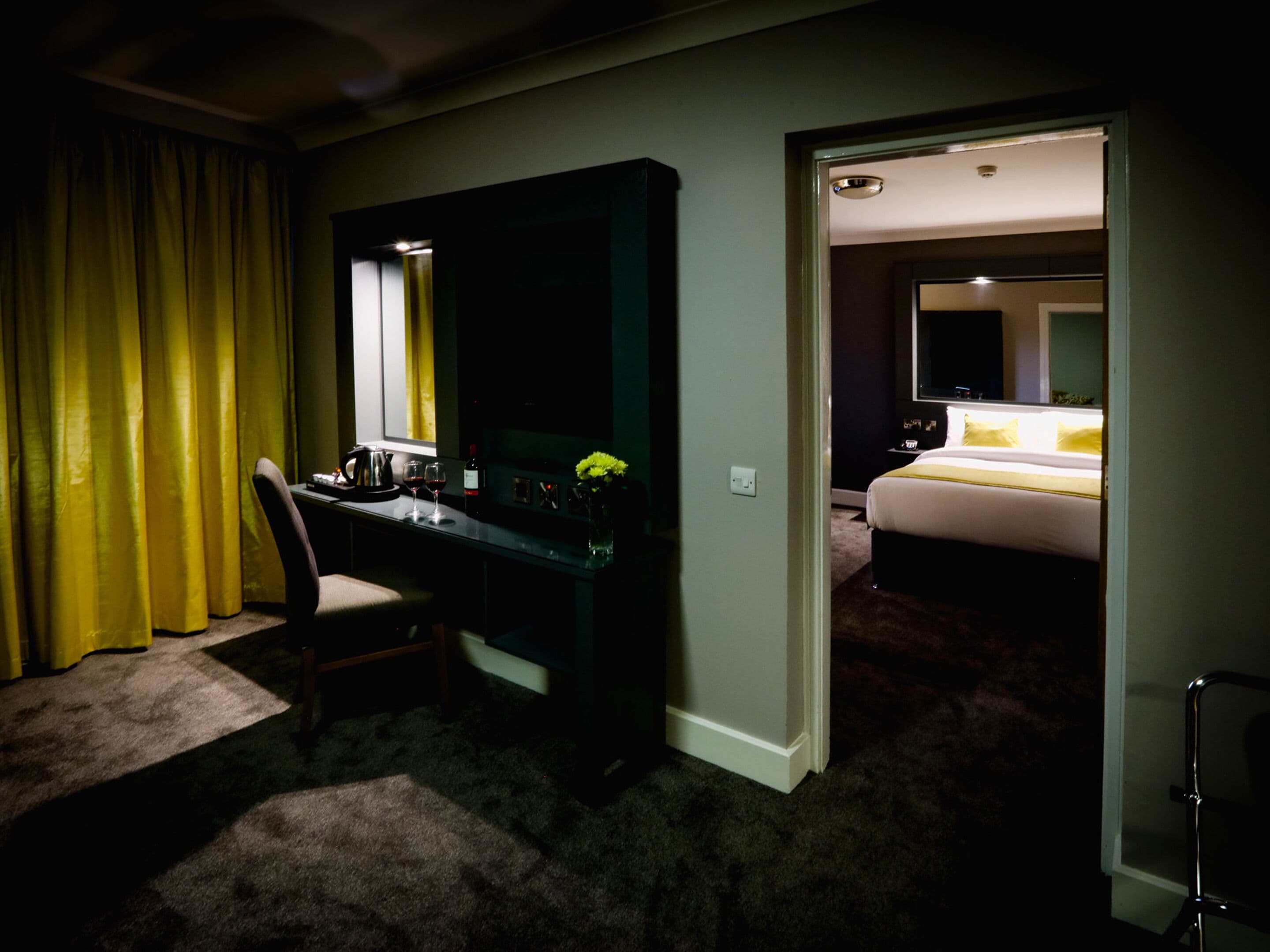 A hotel room with a desk, chair, and a bed.