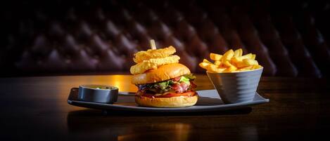 A burger with a side of fries and a small bowl of sauce on a tray.