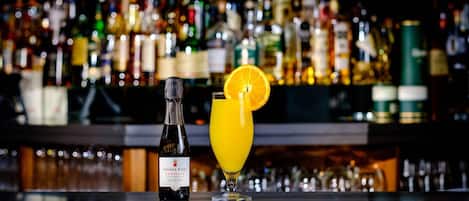Un bar con una botella de Teresa Rizzi Prosecco y un vaso de zumo de naranja con una rodaja de naranja.