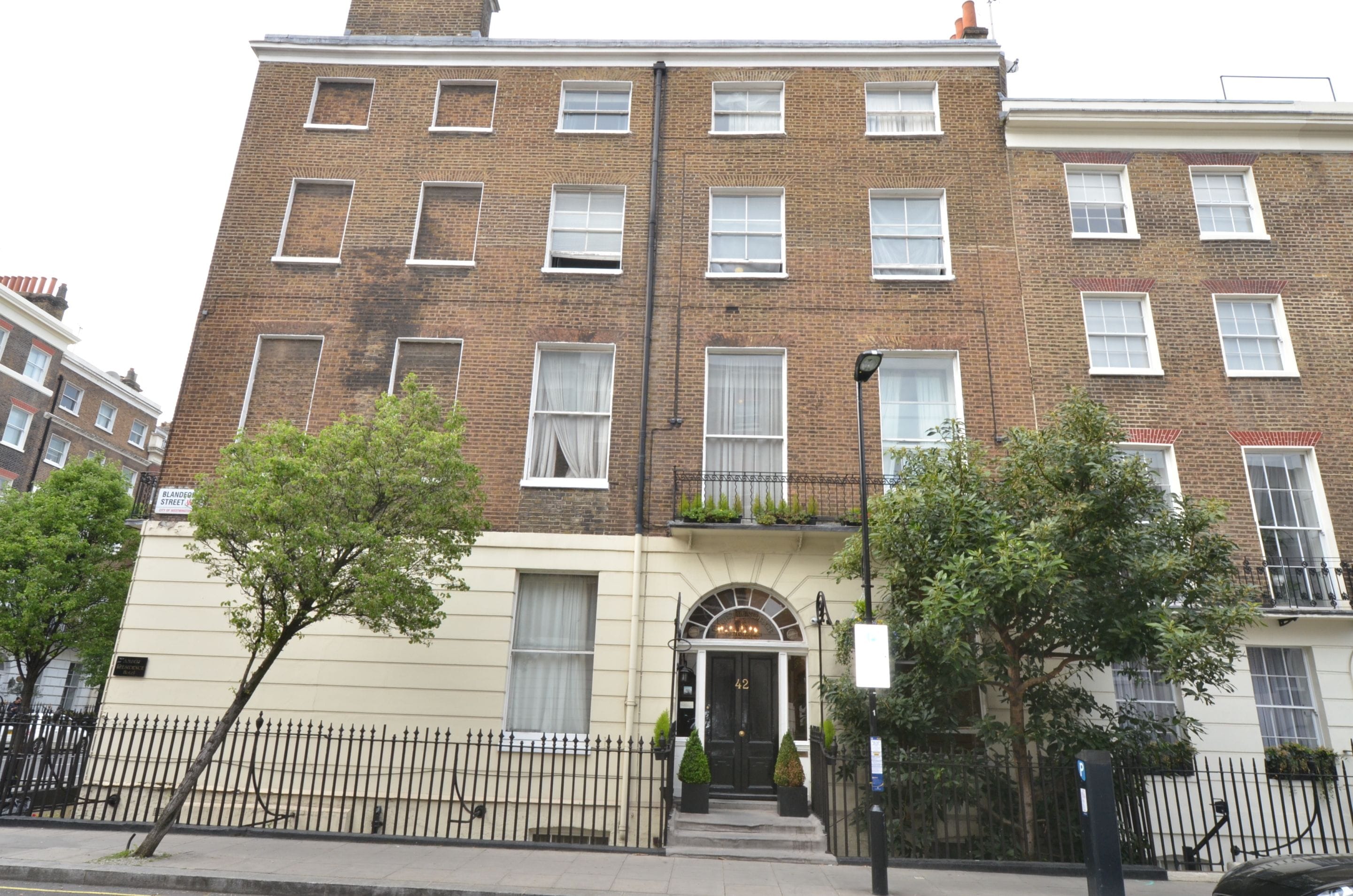 A multi-story brick building with a flat facade, multiple windows, and a front entrance with a door and a small awning.