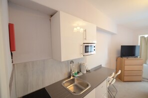 Eine moderne Küche mit Edelstahlspüle, einer Mikrowelle und einem Flachbildfernseher auf einem Holzkasten.