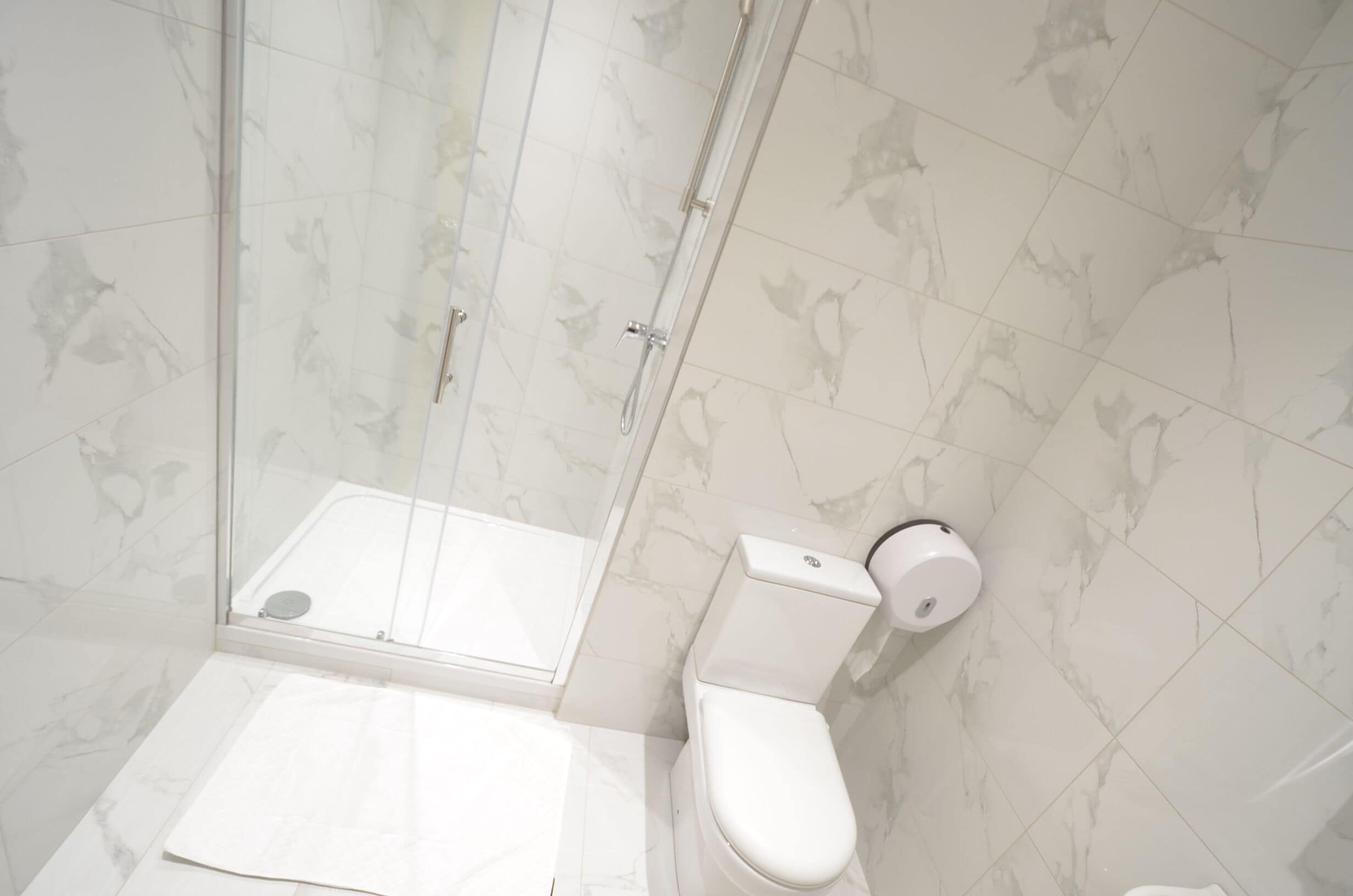A modern bathroom with a glass shower enclosure, a toilet, and a bidet.