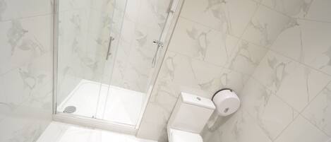 A modern bathroom with a glass shower enclosure, a toilet, and a bidet.