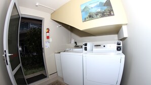 A laundry area with two white washing machines, a fire extinguisher, and a door leading outside. - ASURE Centrepoint Motel (Christchurch)