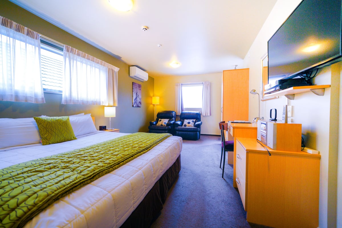 A hotel room with a bed, a desk, a chair, and a television.