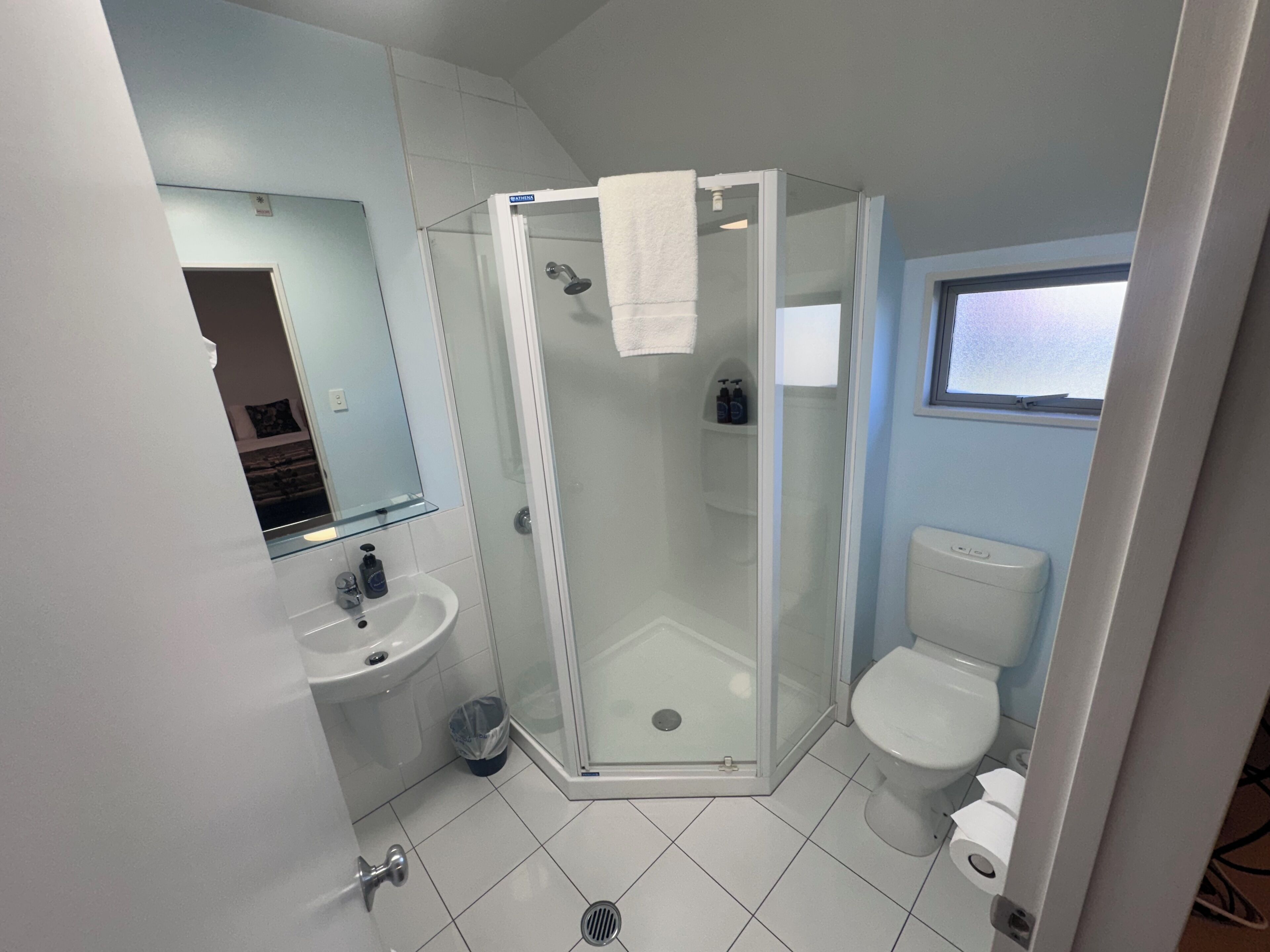 Un baño con ducha de vidrio, lavamanos blanco y un inodoro.