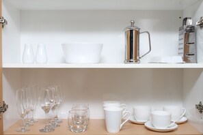 Une cuisine bien rangée, avec des meubles blancs, une machine à café et divers ustensiles de cuisine blancs.