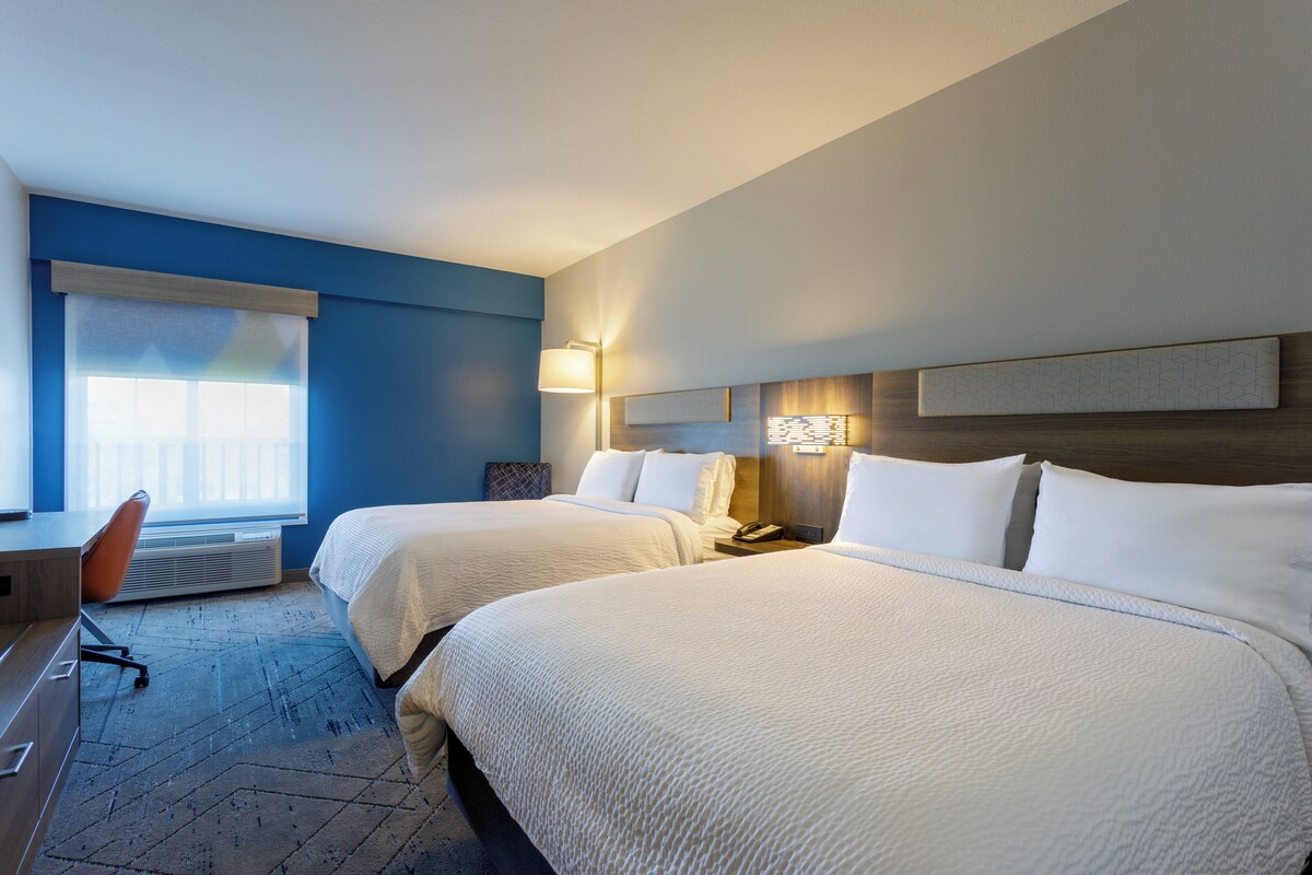 Een hotelkamer met twee bedden, een bureau en een stoel.