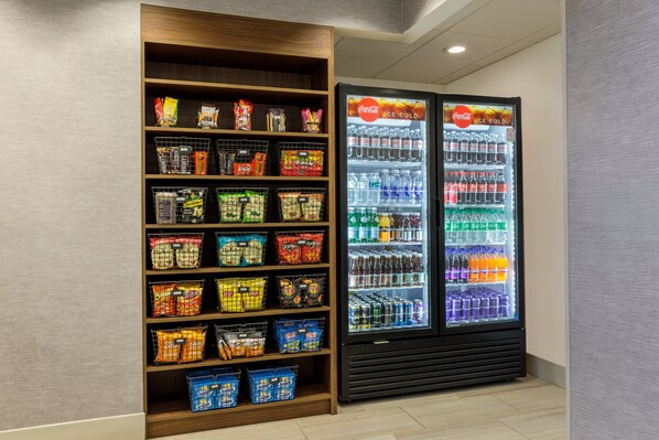 Een automaat gevuld met snacks en een Coca-Cola koelkast.