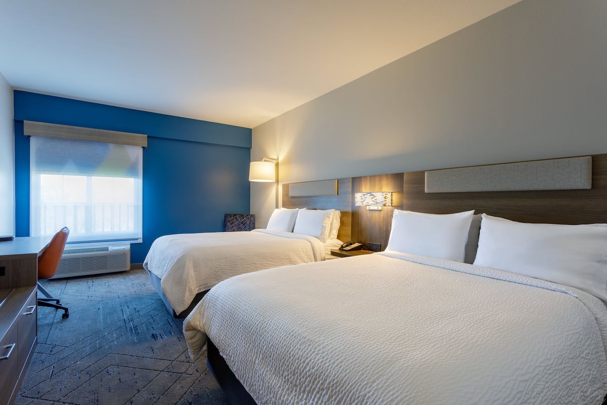 Habitación de hotel con dos camas, un escritorio y una silla.
