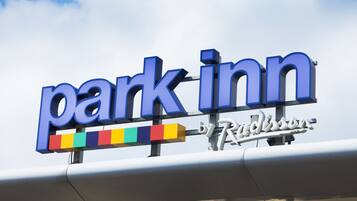 A sign for a Park Inn hotel with a colorful stripe below the name.
