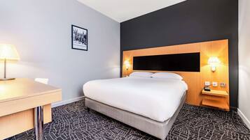 Ein Hotelzimmer mit Bett, Nachttischen, einem Schreibtisch und einem gemusterten Teppich.