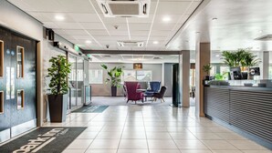 A hotel lobby with a reception desk, seating area, and potted plants.