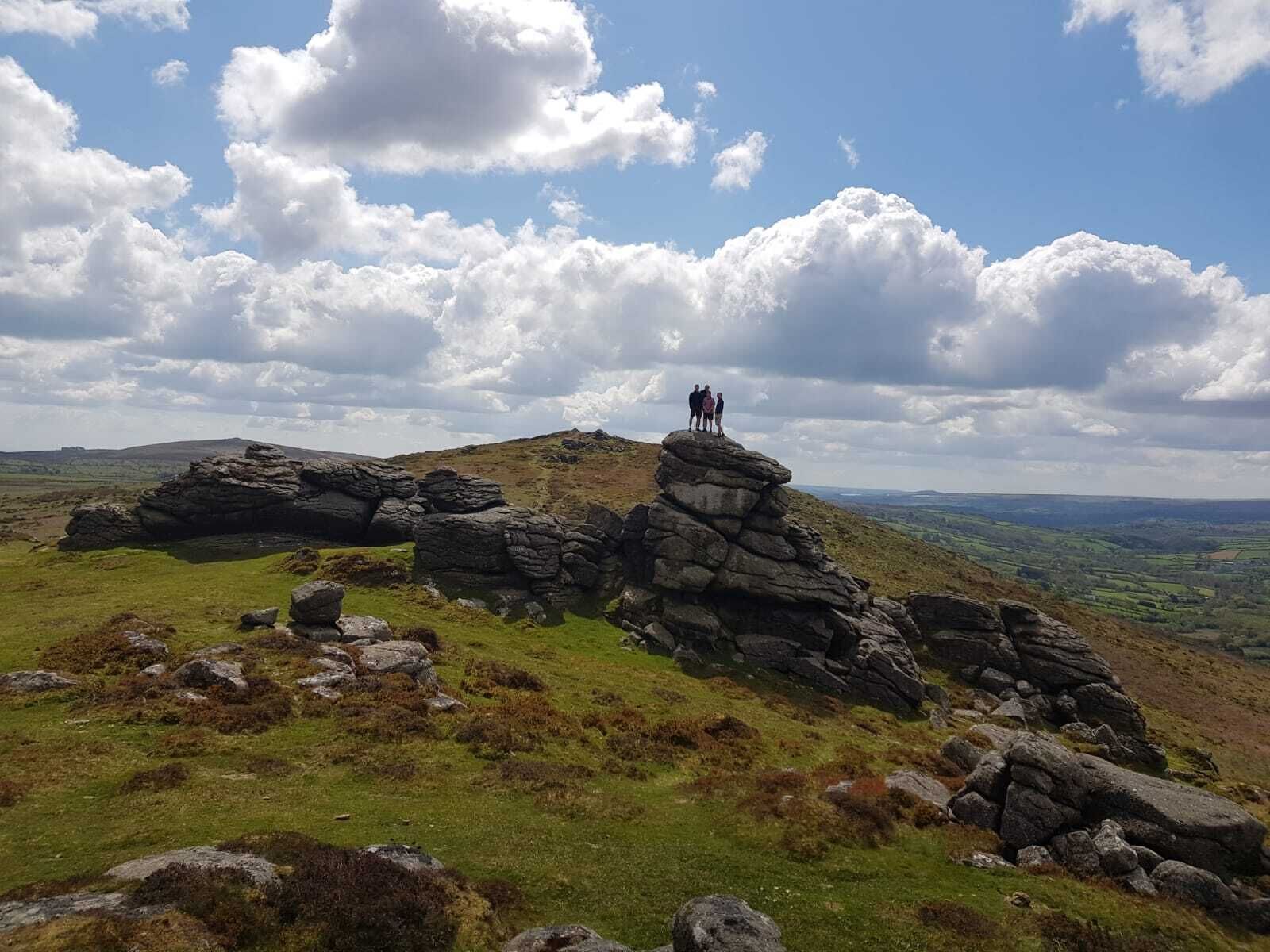 A rocky hilltop with a small group of people standing on a rock formation.